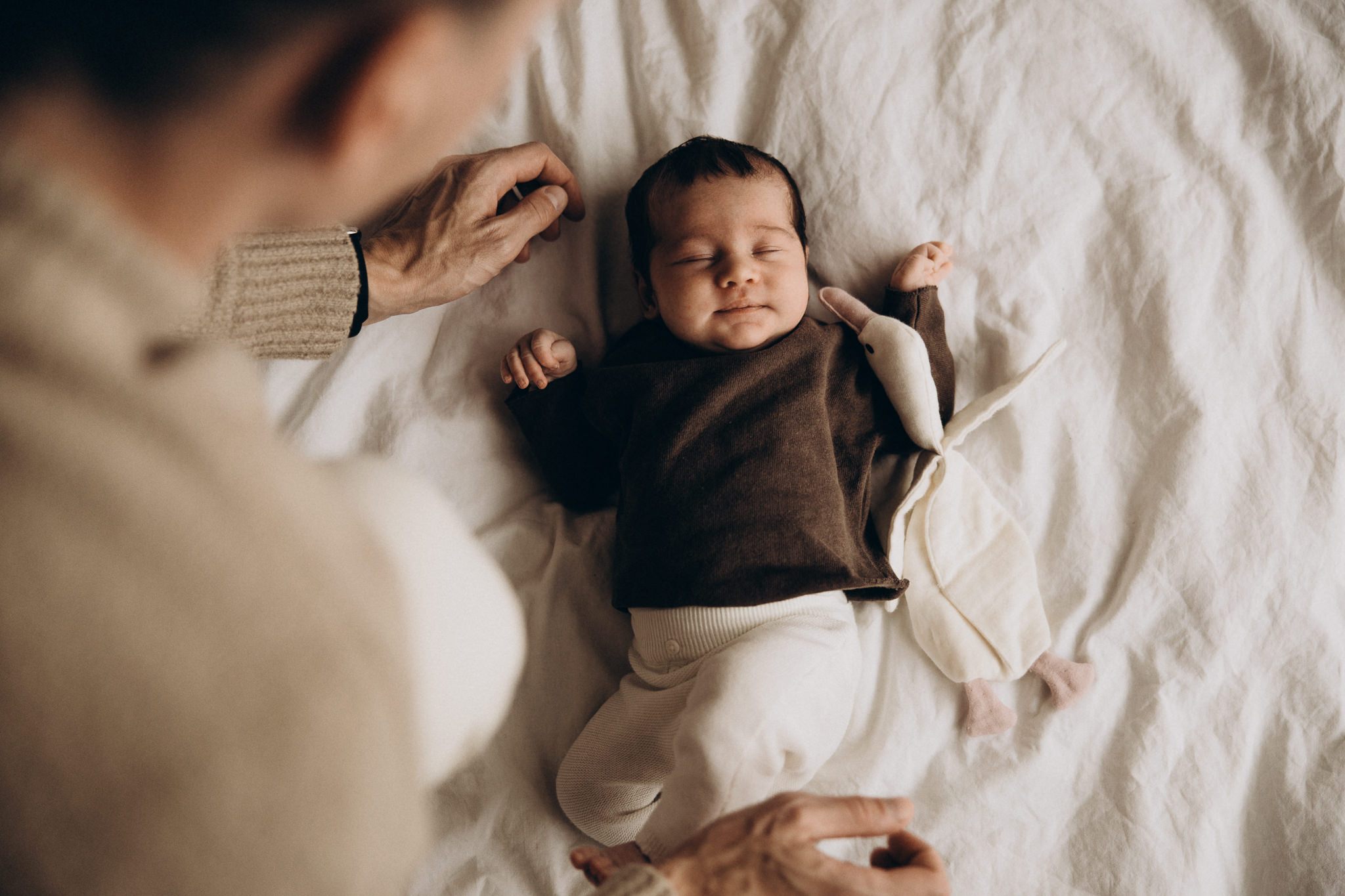 Neugeborenes Baby liegt entspannt auf einer weißen Decke